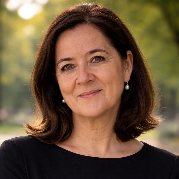 Trauerrednerin Jacqueline Turowsky mit mittellangen, braunen Haaren, Perlenohrringen und schwarzem Oberteil